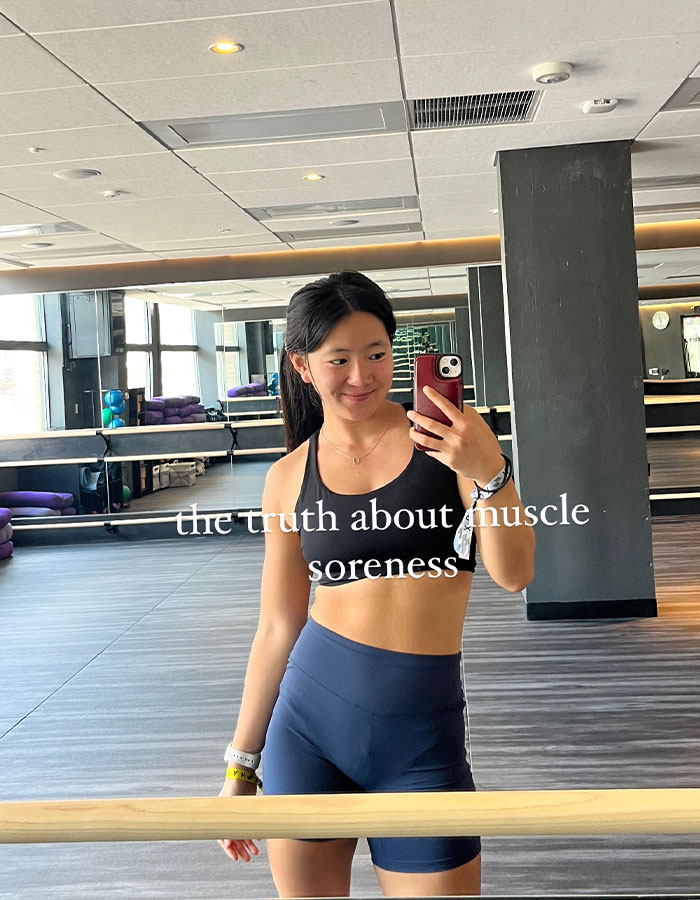 Young woman in workout attire taking a selfie in a Pilates studio amid Gen Z influencer backlash about Pilates supporting patriarchy. Young woman in workout attire taking a selfie in a Pilates studio amid Gen Z influencer backlash about Pilates supporting patriarchy.