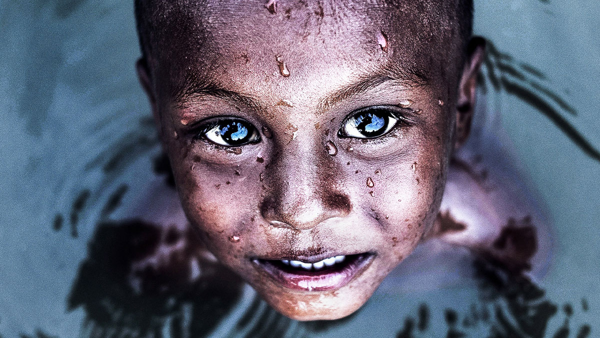 Close-up portrait of a child with water droplets on their face, highlighting beautiful human diversity and unique features