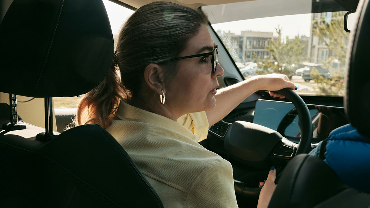 A private investigator driving a car, wearing glasses and focused on a case, highlighting weirdest cases investigations.