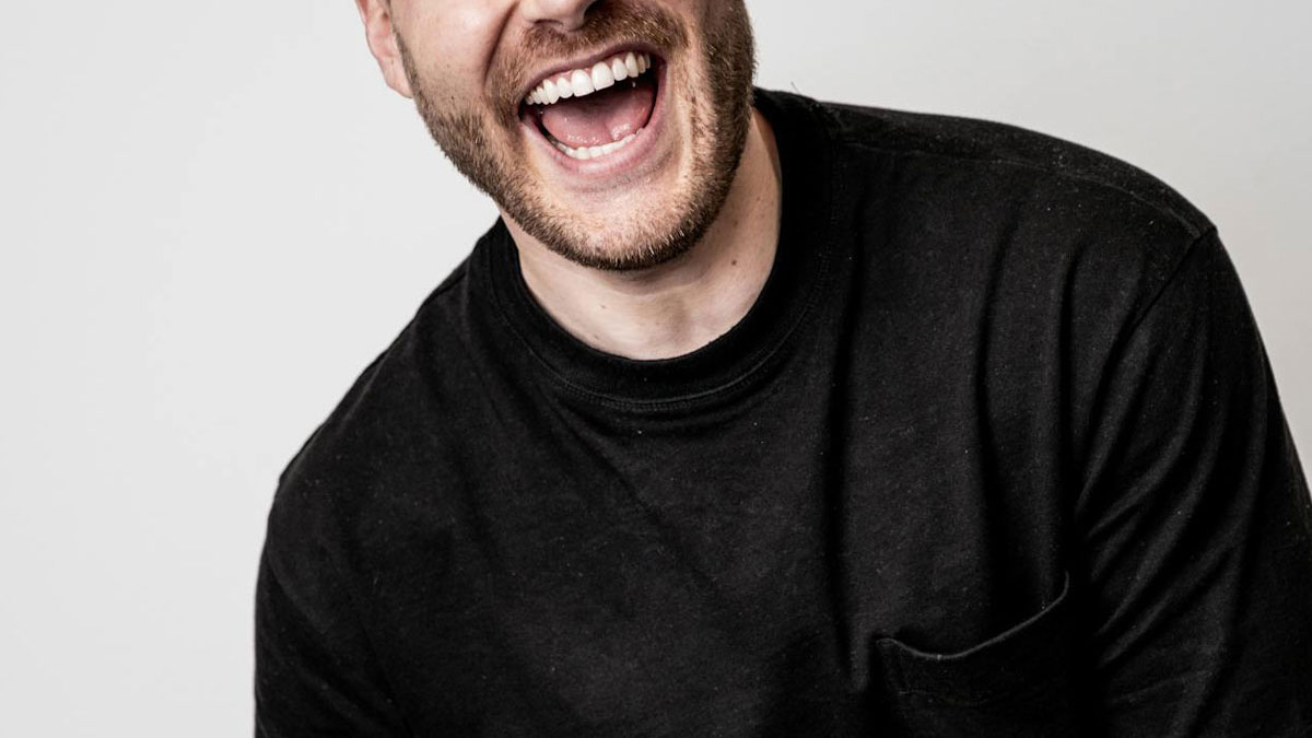 Man in black shirt smiling widely, representing a private resort worker answering questions in an AMA session.