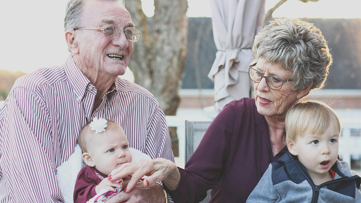 Elderly couple interacting with two children outdoors, highlighting generational differences in modern parents.