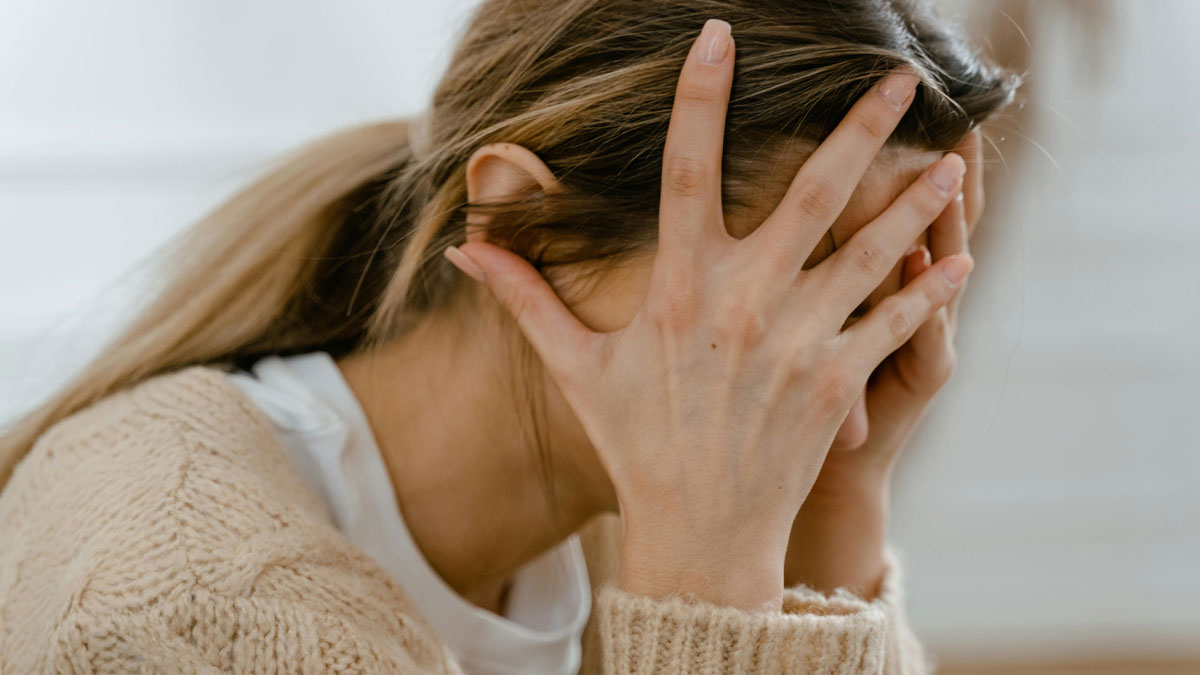 Woman covering face with hands, showing stress and emotion related to psychological clues in dreams about people.