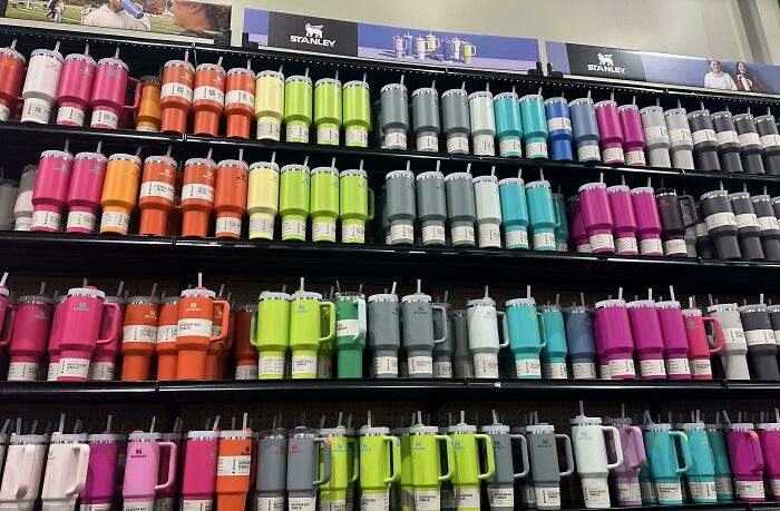 Rows of colorful reusable drinkware displayed on shelves highlighting trends contributing to overconsumption concerns.