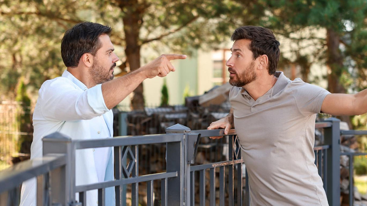Two men arguing near a fence about a public road used as a personal parking space outside a house