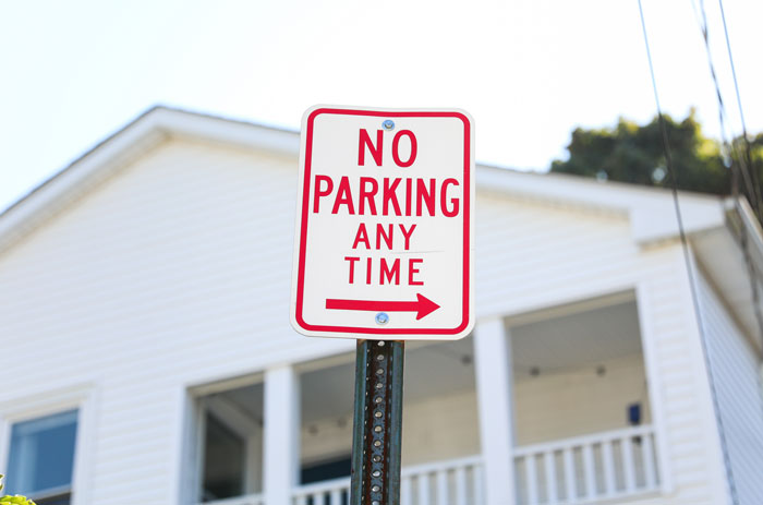 No parking any time sign on a public road in front of a house enforcing parking space rules. No parking any time sign on a public road in front of a house enforcing parking space rules.