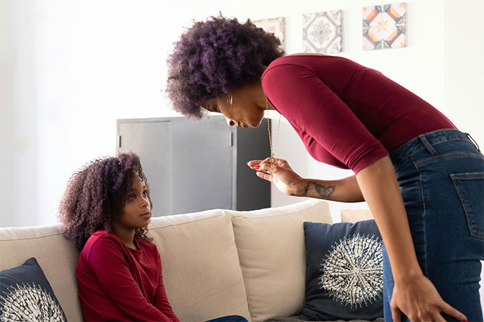 Woman with PhD leaning forward, speaking seriously to a young girl on a couch in a brightly lit living room. Woman with PhD leaning forward, speaking seriously to a young girl on a couch in a brightly lit living room.