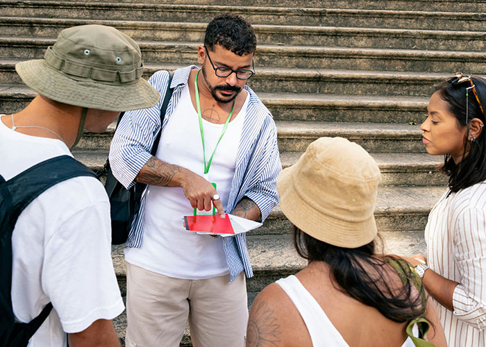 Tour guide showing map to group of tourists on stairs, highlighting family tour amidst childfree couple controversy.