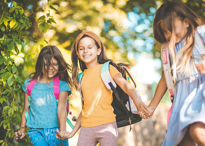 Three girls holding hands and walking outdoors, representing family tour experiences amid childfree couple controversies.