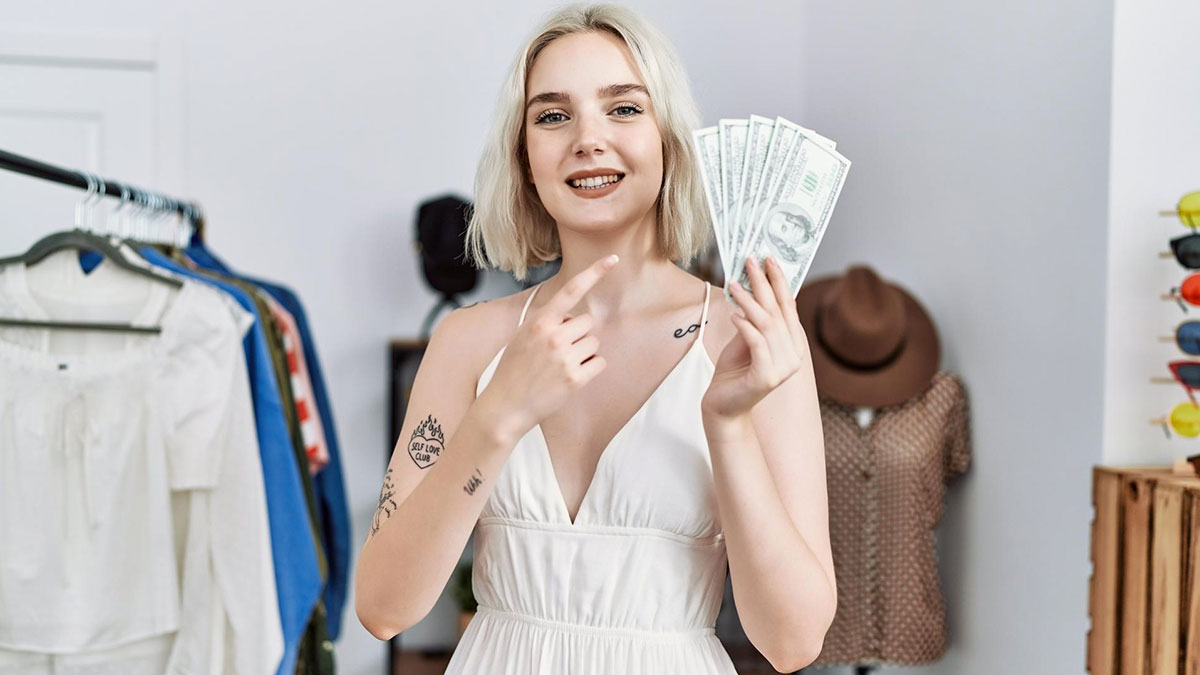 Smiling woman holding cash and pointing at money, illustrating a groom discount and refusal to lend $2K tension.