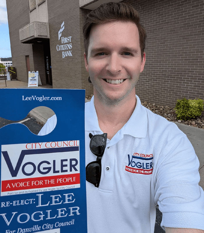 Virginia councilman Lee Vogler smiling outdoors, wearing a campaign shirt with city council election signage. Virginia councilman Lee Vogler smiling outdoors, wearing a campaign shirt with city council election signage.