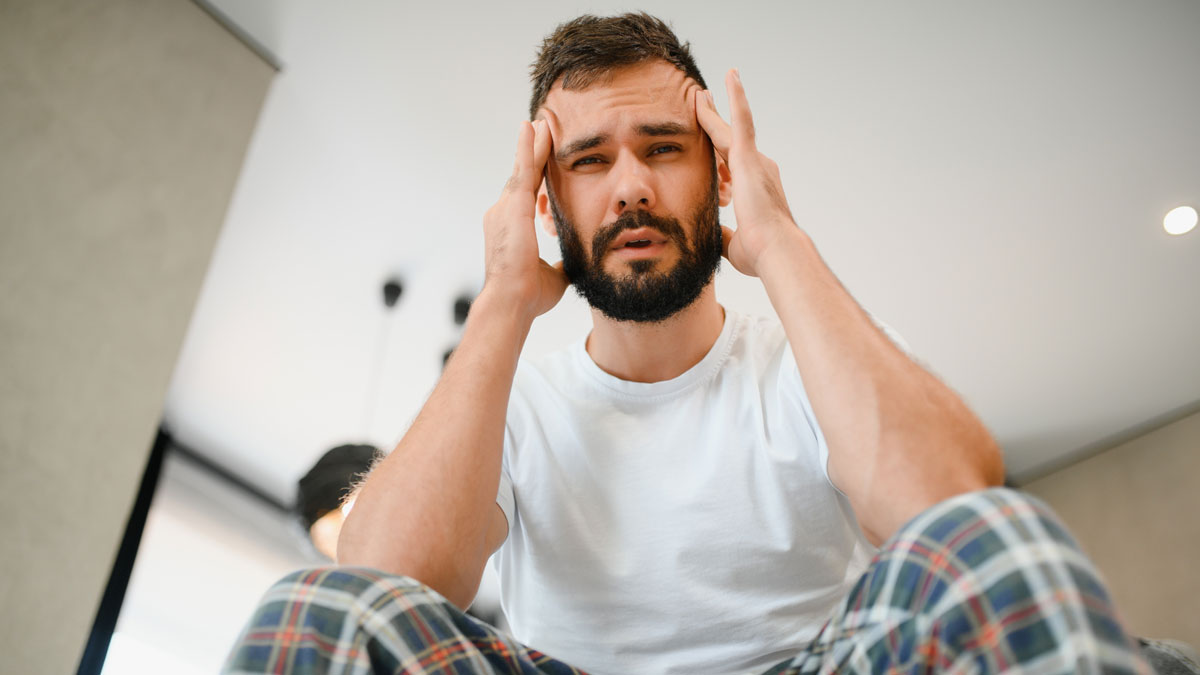Man in casual clothes holding his head, appearing stressed, representing experience overlooked and rejection concerns.