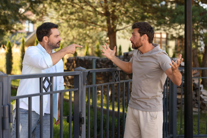 Two men arguing intensely outdoors near a fence, illustrating conflict with a late-night neighbor over a smart air con device. Two men arguing intensely outdoors near a fence, illustrating conflict with a late-night neighbor over a smart air con device.
