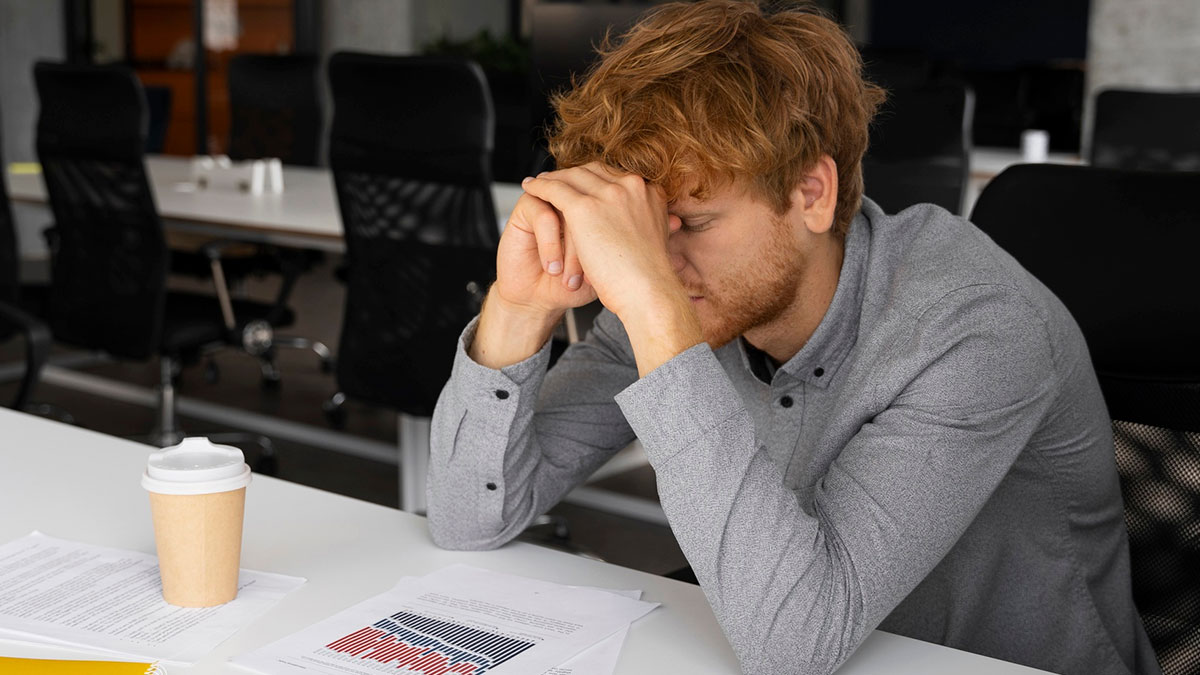 Worried worker at office desk with papers, stressed after being team leadu2019s scapegoat and labeled a snitch.