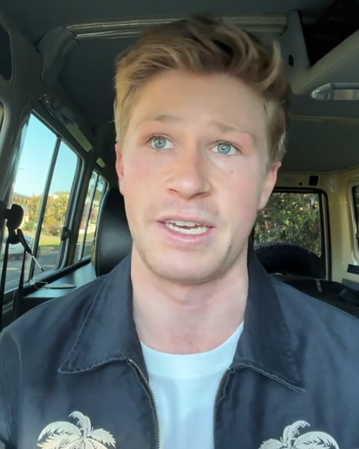 Robert Irwin wearing a black jacket with palm trees speaking inside a parked vehicle during daytime. Robert Irwin wearing a black jacket with palm trees speaking inside a parked vehicle during daytime.