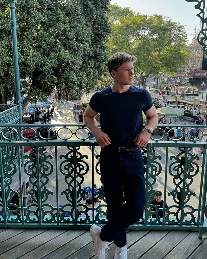 Young man at a popular outdoor Australian restaurant balcony during the day with trees and people in the background. Young man at a popular outdoor Australian restaurant balcony during the day with trees and people in the background.