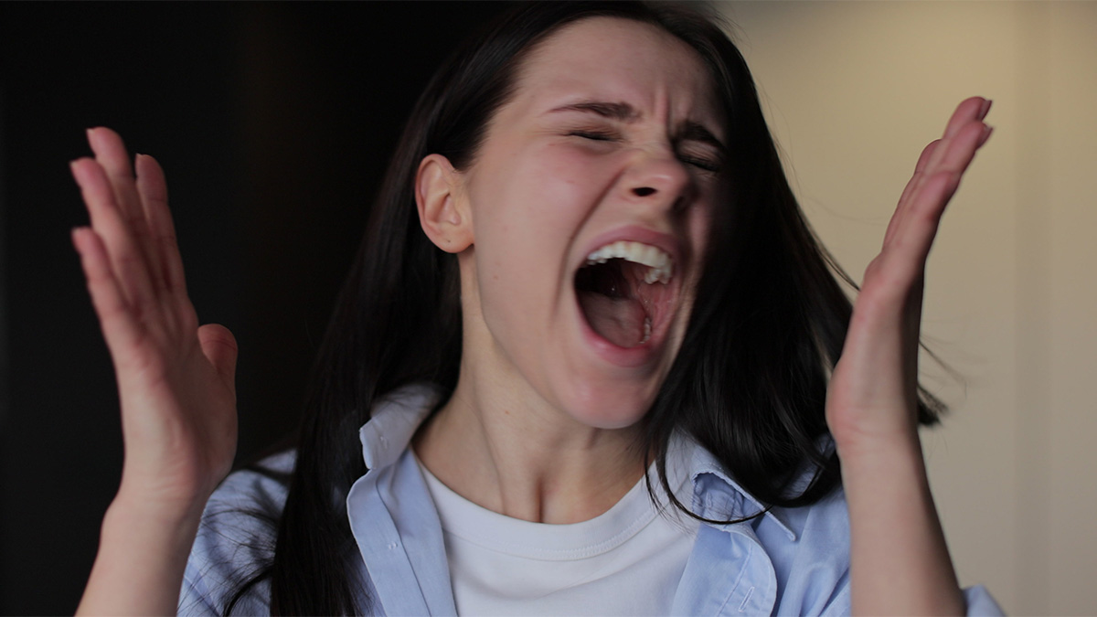 Woman with dark hair expressing frustration and anger while reacting intensely to a triggering situation involving Jewish traditions and OCD.