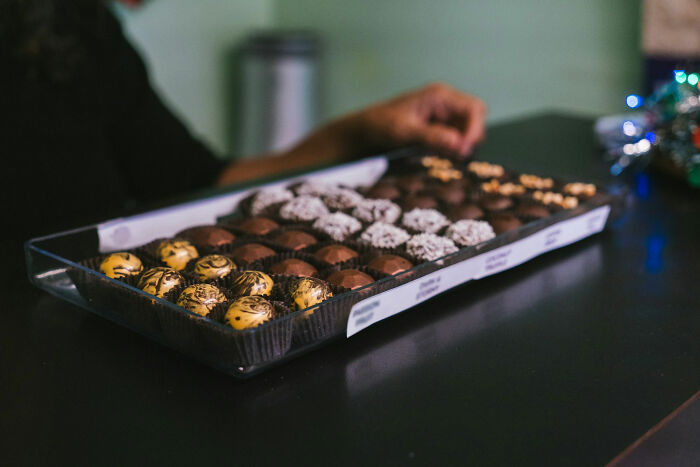 Person reaching for chocolates in a box on a table, illustrating how people took revenge on their bosses.