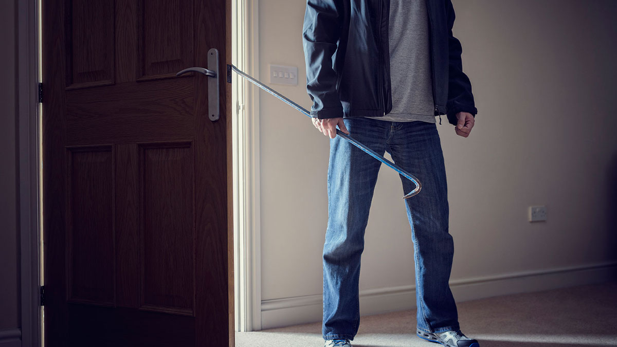 Person in casual clothes holding a crowbar near a door, evoking creepy real things witnessed or heard about.