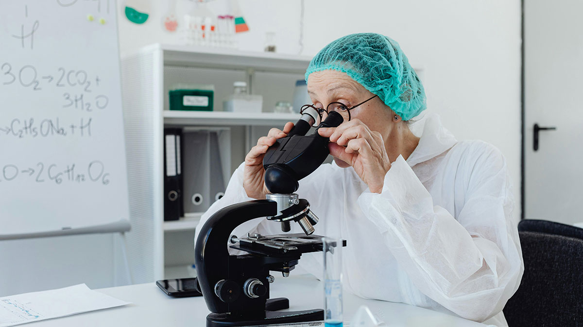 Scientist examining samples under a microscope in a lab focused on cadaver science research and analysis.