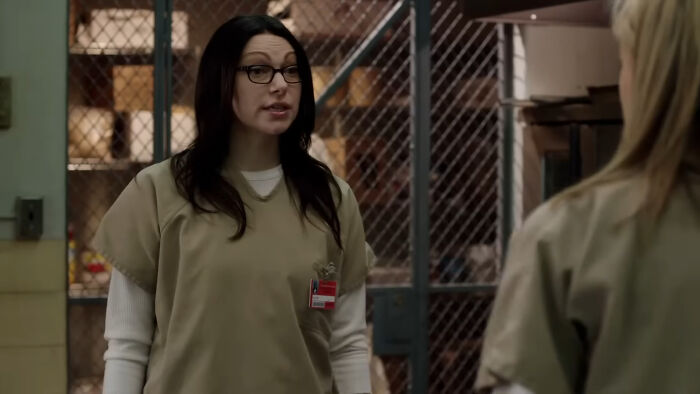 Female actor in prison attire speaking with another person in a scene showing actors who auditioned for heroes but became iconic villains