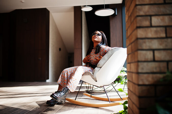 Woman sitting in a modern rocking chair indoors, reflecting on powerful sentences that changed people’s lives.