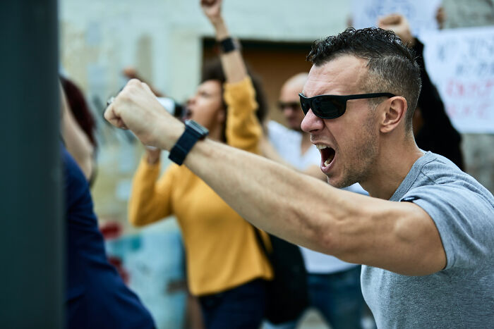 Man wearing sunglasses passionately shouting with raised fist during a protest about sentences that changed people's lives.