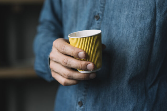 Person wearing a blue shirt holding a yellow cup, symbolizing reflection on sentences that changed people's lives.