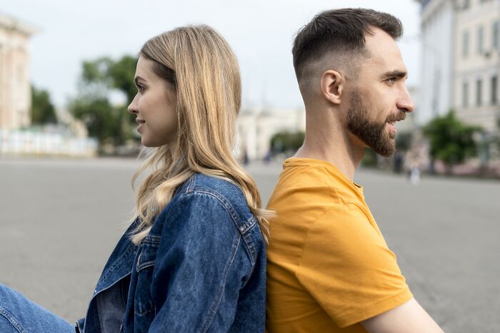Young man and woman sitting back to back outdoors, reflecting on life-changing sentences that impact people’s lives.