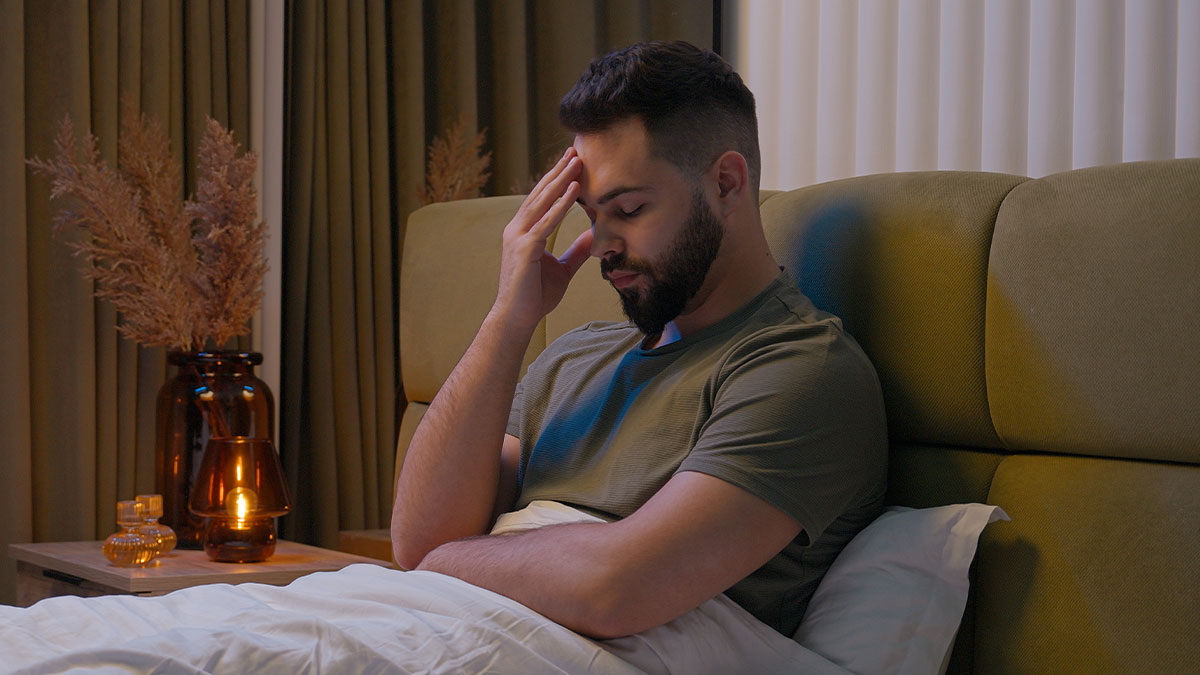 Man sitting in bed with hand on forehead, reflecting deeply, illustrating sentences that changed people's lives.