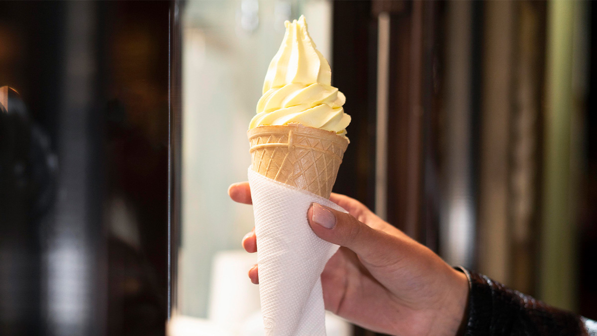 Hand holding a soft serve ice cream cone wrapped in a napkin, illustrating secrets revealed by former employees.