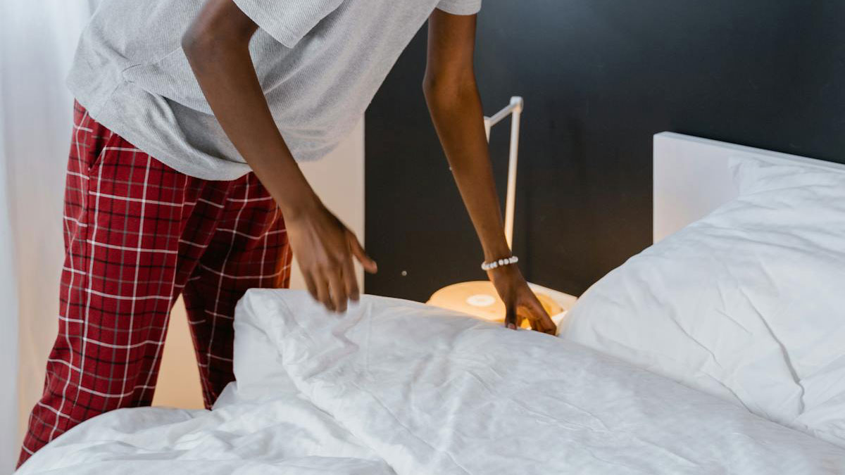 Person in red plaid pajama pants making a bed, illustrating common cheating red flags in relationships.