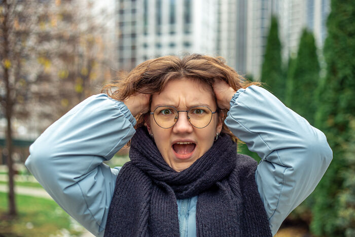 Young woman outdoors looking frustrated, holding her head, illustrating signs you grew up sheltered.