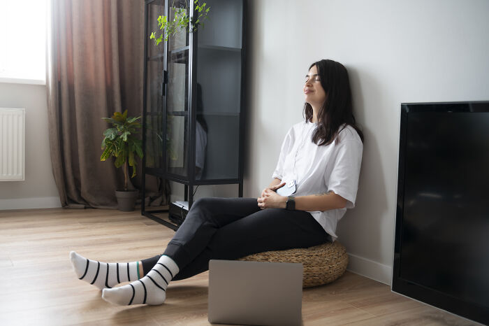 Young woman sitting relaxed on floor in cozy room, reflecting quietly, illustrating signs grew up sheltered concept.