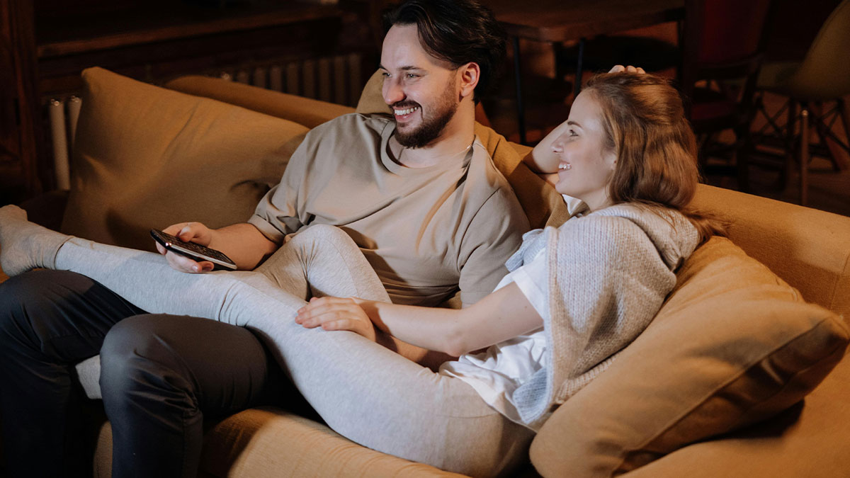 Couple lounging on the couch together, enjoying a relaxed moment in a cozy living room setting.