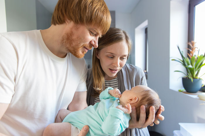 Couple admiring their newborn baby in a bright room, highlighting themes of baby naming and family relationships. Couple admiring their newborn baby in a bright room, highlighting themes of baby naming and family relationships.