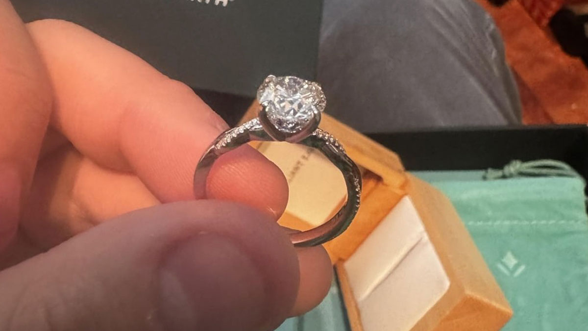 Close-up of engagement ring with a small diamond held by hand, highlighting size debate in proposal rings.