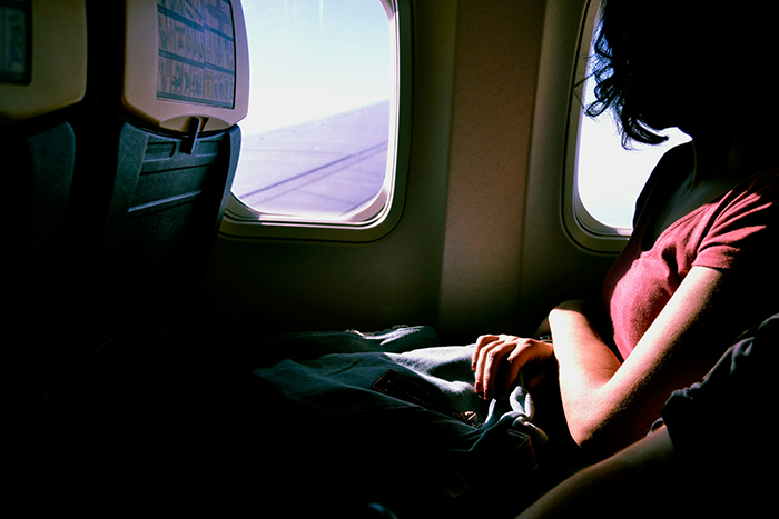 Woman sitting by airplane window, experiencing personal space invasion after declining to swap seats during flight.