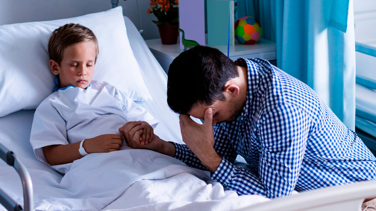 Father holding sick child's hand in hospital, facing emotional moment while ready to save his childu2019s life.