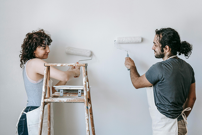 Couple painting a wall together, representing a wife discovering her husband secretly owns and rents his mom’s house. Couple painting a wall together, representing a wife discovering her husband secretly owns and rents his mom’s house.