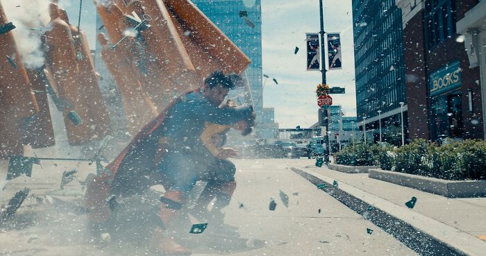 Superman reboot action scene with flying debris and blurred background in an urban setting.