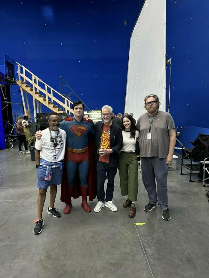 Cast and crew posing on set with actor in Superman costume during the woke Superman reboot film production.
