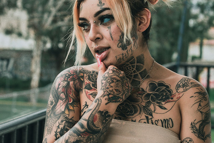 Woman with extensive tattoos on face, neck, and arms, representing tattoo artists who decline jobs on moral grounds. Woman with extensive tattoos on face, neck, and arms, representing tattoo artists who decline jobs on moral grounds.
