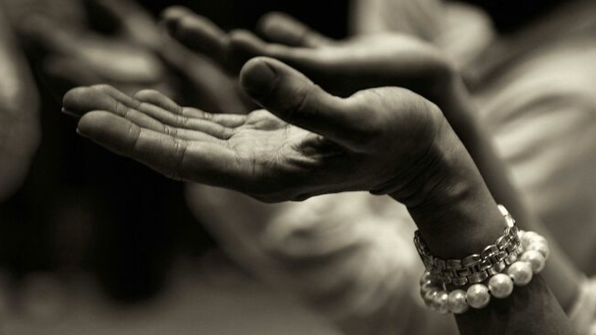 Close-up of open hands raised in a gesture of prayer or meditation, symbolizing theories about the afterlife.