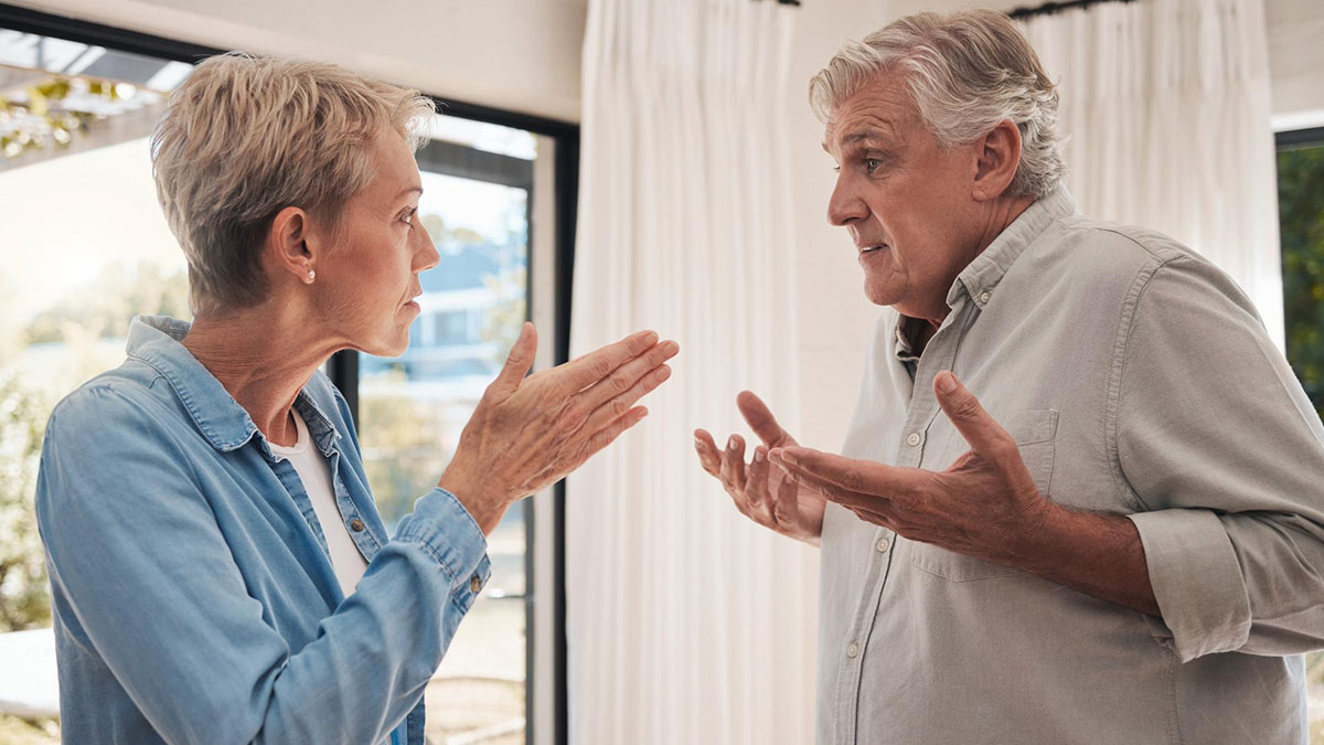 Mature couple having a heated discussion indoors, highlighting changing social customs including thank you notes fading away.