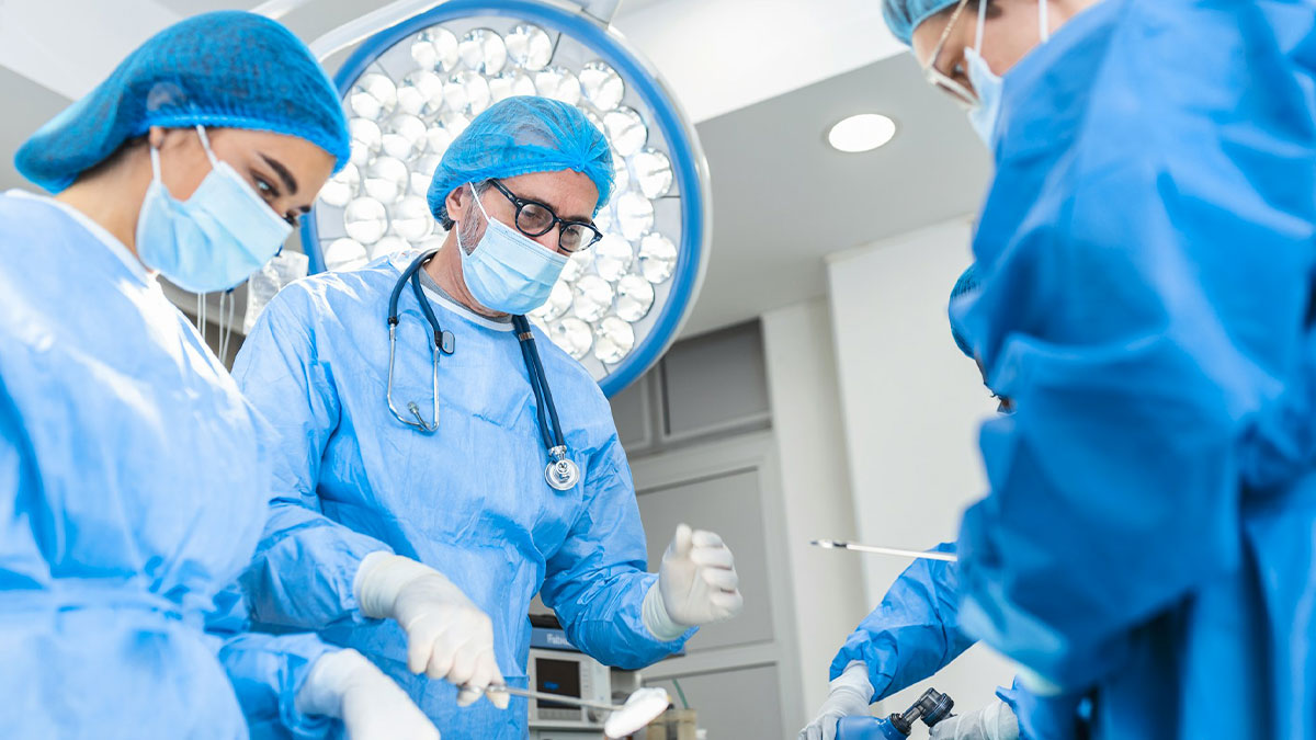 Surgical team in blue scrubs performing an operation under bright operating room lights focused on medical teamwork.