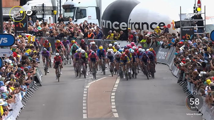 Cyclists racing at the Tour De France with fans crowded on grave sites for a better view, sparking outrage among viewers. Cyclists racing at the Tour De France with fans crowded on grave sites for a better view, sparking outrage among viewers.