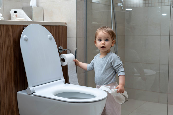 Toddler in bathroom holding toilet paper near toilet, unrelated to lady parking in couple's private space keyword. Toddler in bathroom holding toilet paper near toilet, unrelated to lady parking in couple's private space keyword.
