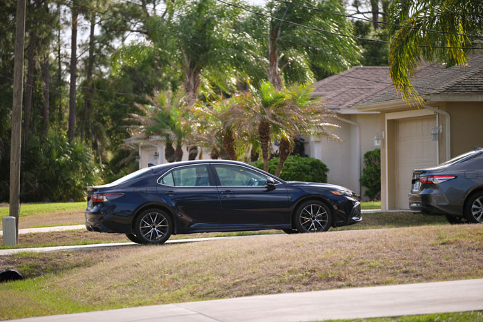 Black sedan parked in a suburban driveway with another car blocking its exit, illustrating private parking conflict. Black sedan parked in a suburban driveway with another car blocking its exit, illustrating private parking conflict.