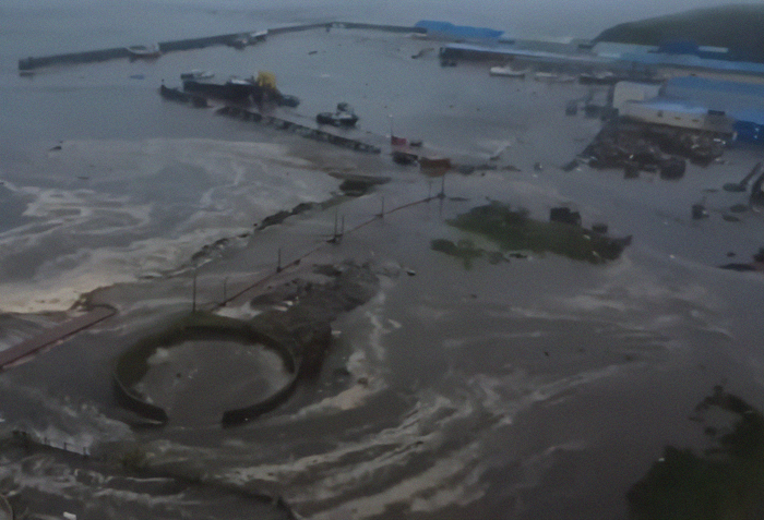 Flooded coastal area with strong tsunami waves hitting the shore after mega earthquake, showing damaged structures and rising waters. Flooded coastal area with strong tsunami waves hitting the shore after mega earthquake, showing damaged structures and rising waters.