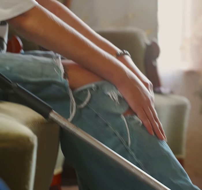 Person wearing ripped jeans seated indoors with a walking cane, symbolizing model with broken limbs and spine recovery. Person wearing ripped jeans seated indoors with a walking cane, symbolizing model with broken limbs and spine recovery.